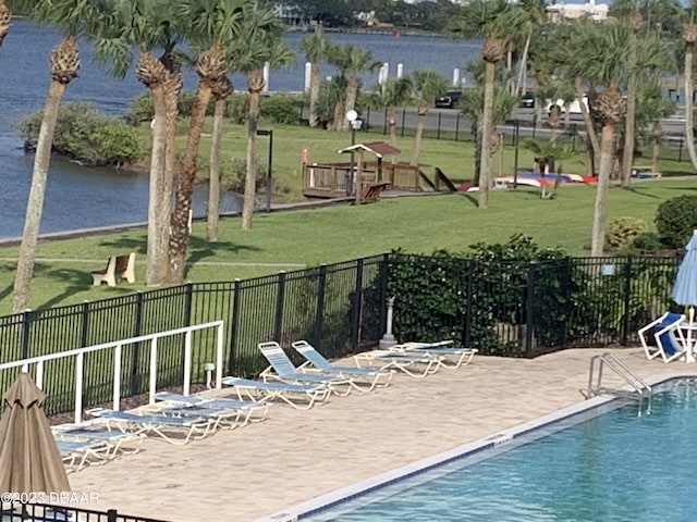 view of swimming pool featuring a yard, a patio, and a water view