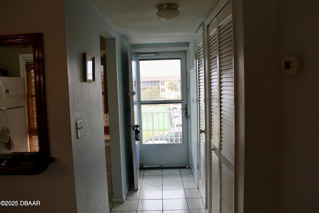 corridor featuring light tile patterned floors and a textured ceiling