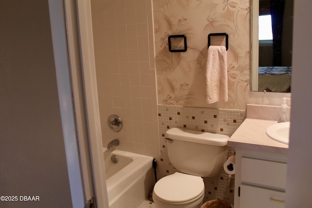 full bathroom featuring tiled shower / bath, vanity, toilet, and tile walls