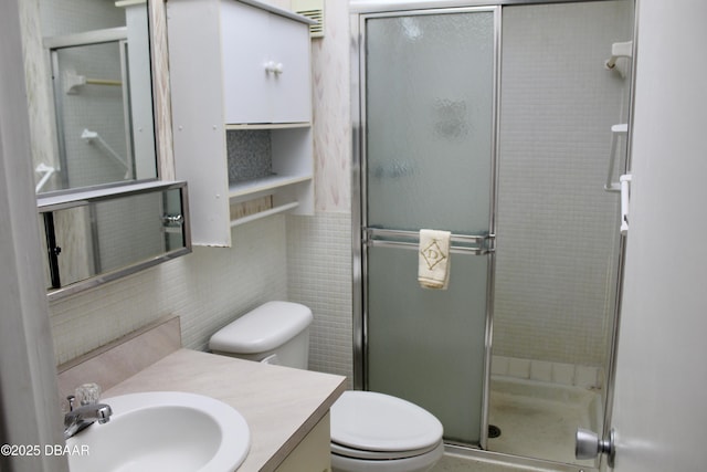 bathroom with toilet, tasteful backsplash, tile walls, vanity, and a shower with door