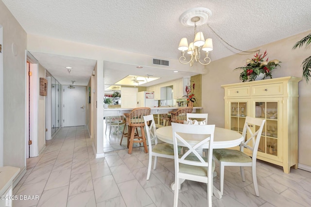 2425 S Atlantic Ave Unit 202, Daytona Beach, FL 32118 - dining area with a chandelier, a textured ceiling, and light marble finish flooring