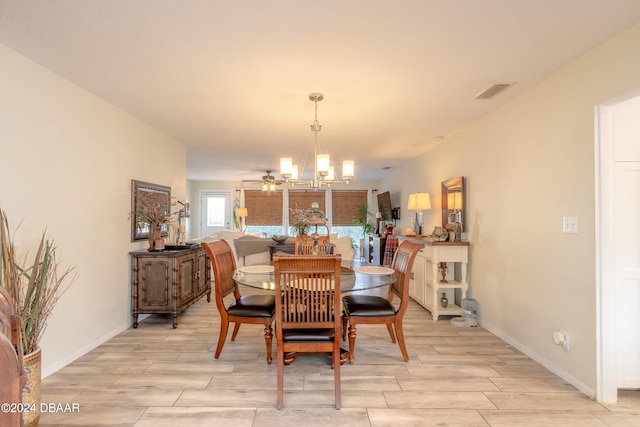 dining area with light wood-type flooring and ceiling fan with notable chandelier