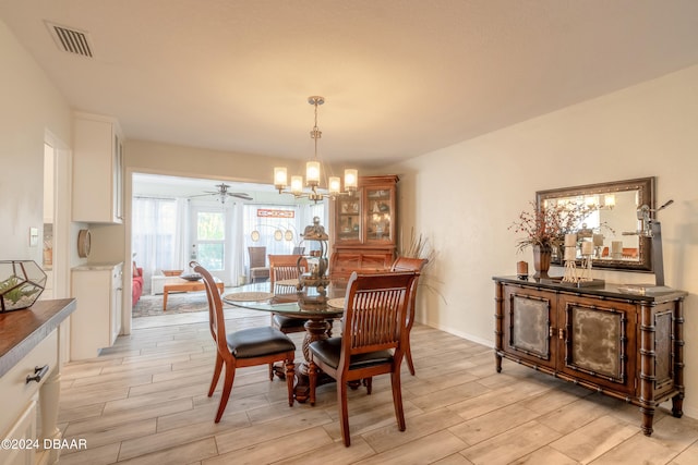 dining room featuring ceiling fan with notable chandelier and light wood-type flooring