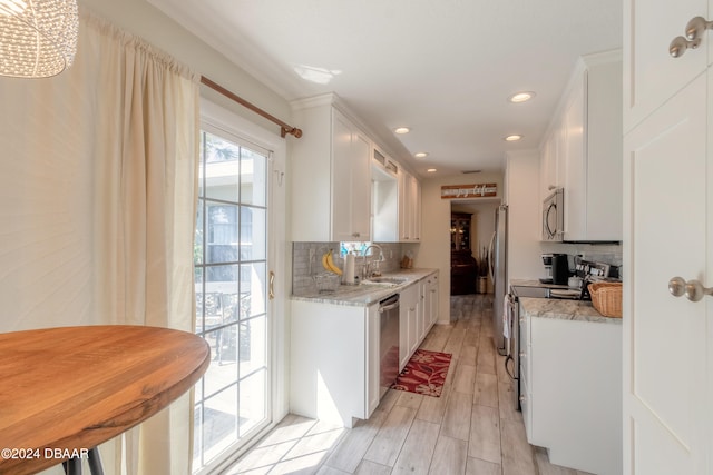 kitchen featuring tasteful backsplash, light stone countertops, stainless steel appliances, and white cabinets