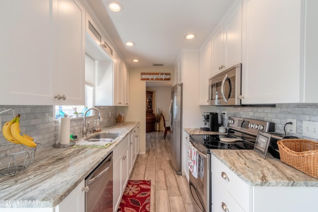 kitchen featuring stainless steel appliances, white cabinets, sink, and light hardwood / wood-style flooring