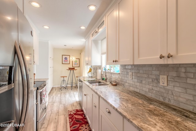 kitchen featuring white cabinets, light hardwood / wood-style flooring, sink, light stone countertops, and appliances with stainless steel finishes