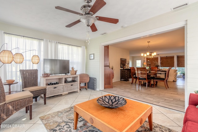 living room with ceiling fan with notable chandelier, light hardwood / wood-style flooring, crown molding, and plenty of natural light