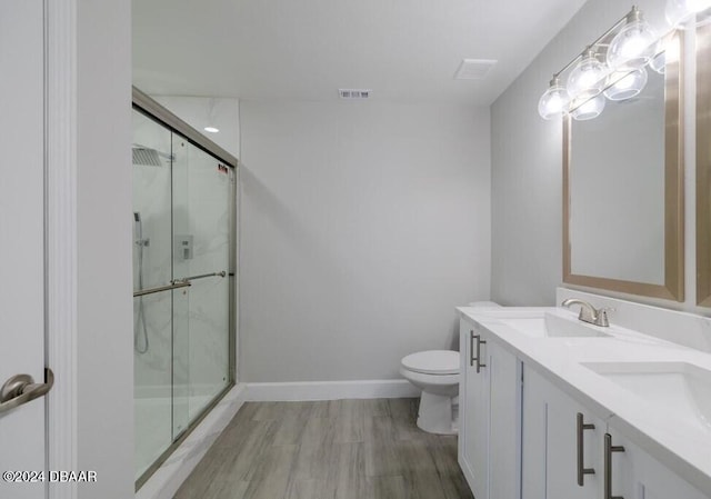 bathroom with toilet, a shower with door, and vanity