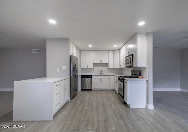 kitchen with light wood-type flooring, appliances with stainless steel finishes, sink, and white cabinetry