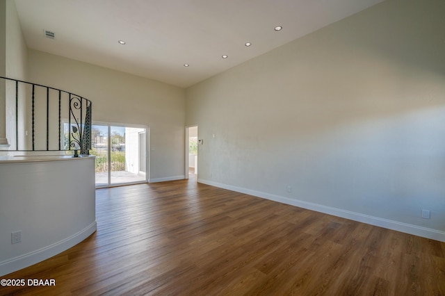 empty room with a towering ceiling and hardwood / wood-style floors