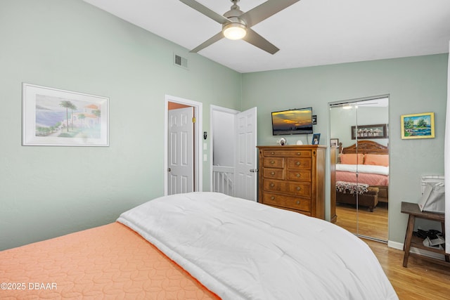 bedroom with hardwood / wood-style flooring, vaulted ceiling, a closet, and ceiling fan