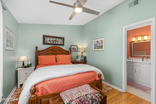 bedroom featuring ensuite bath, vaulted ceiling, light hardwood / wood-style floors, and ceiling fan