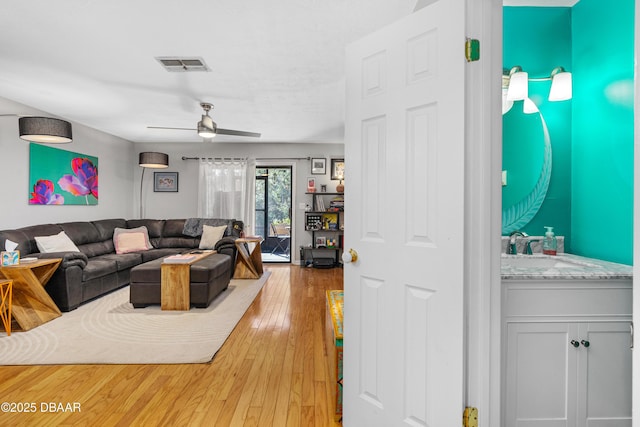 living room featuring sink, hardwood / wood-style floors, and ceiling fan