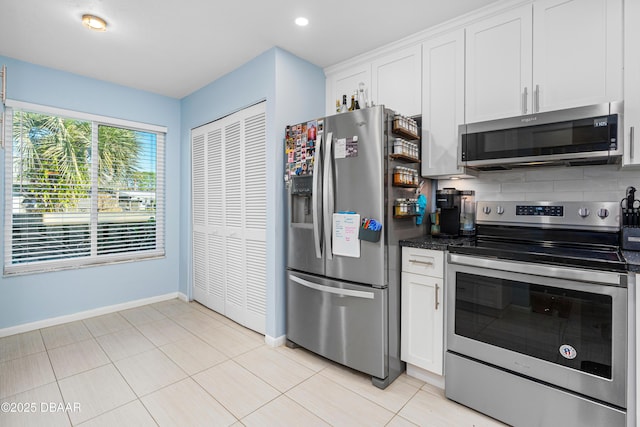 kitchen with stainless steel appliances, white cabinetry, light tile patterned floors, and decorative backsplash