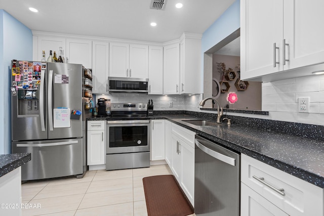 kitchen with sink, dark stone counters, white cabinets, and appliances with stainless steel finishes