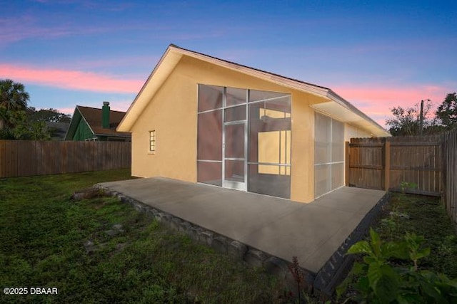 back house at dusk featuring a yard and a patio area