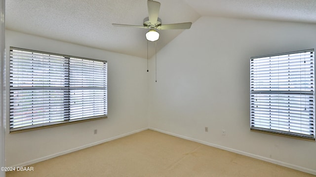 unfurnished room featuring vaulted ceiling, ceiling fan, carpet floors, and a textured ceiling