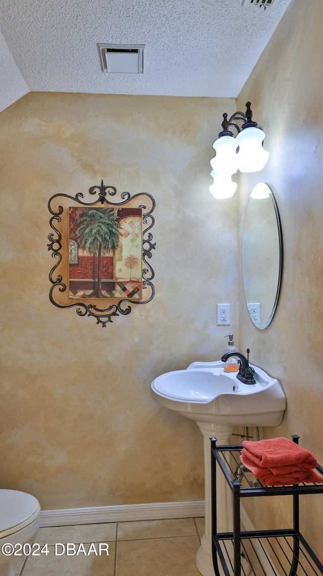 bathroom with toilet, tile patterned floors, and a textured ceiling