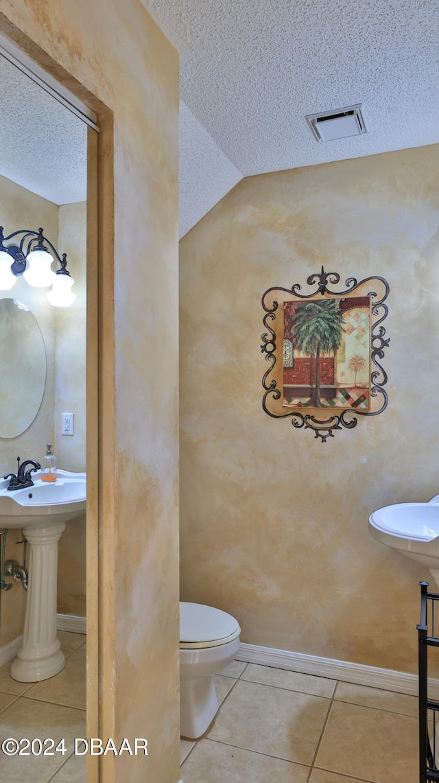 bathroom with vaulted ceiling, tile patterned flooring, a textured ceiling, and toilet