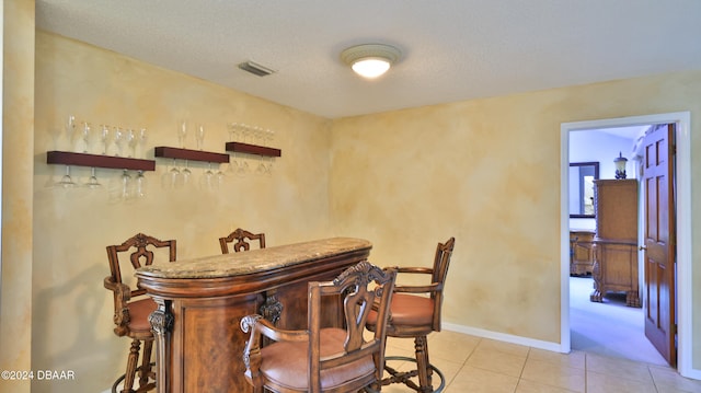 bar with light tile patterned flooring and a textured ceiling