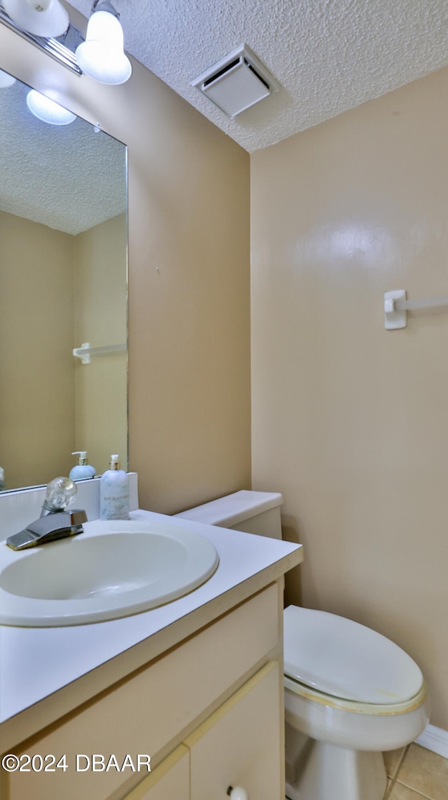 bathroom featuring tile patterned floors, vanity, a textured ceiling, and toilet