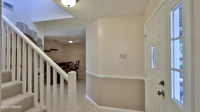 entryway with light tile patterned floors and a textured ceiling