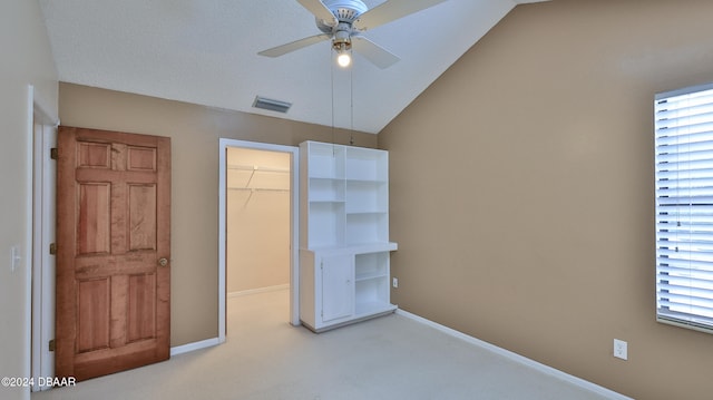 unfurnished bedroom featuring a closet, lofted ceiling, ceiling fan, and a walk in closet