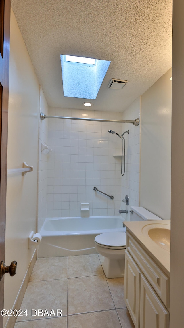 full bathroom featuring a skylight, tiled shower / bath combo, tile patterned floors, and a textured ceiling