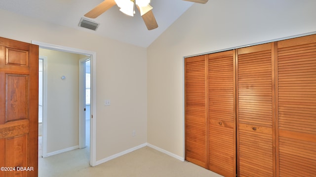 unfurnished bedroom featuring ceiling fan, a closet, light colored carpet, and lofted ceiling