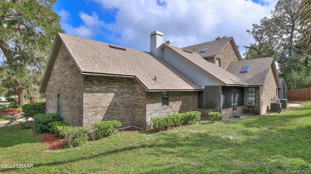 rear view of property featuring a lawn and cooling unit