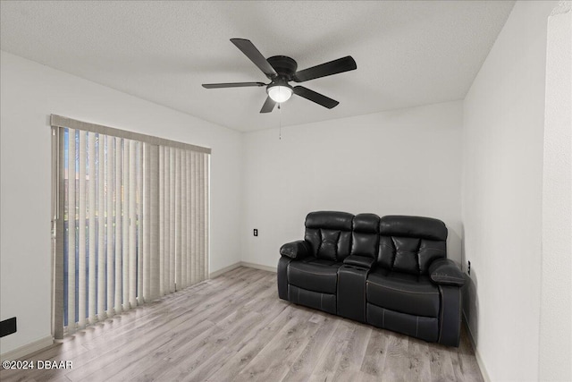 living area with a textured ceiling, light hardwood / wood-style flooring, and ceiling fan