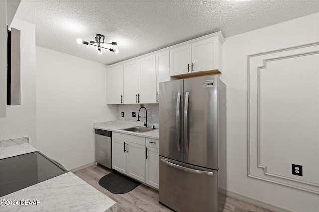 kitchen featuring sink, appliances with stainless steel finishes, tasteful backsplash, white cabinets, and light wood-type flooring