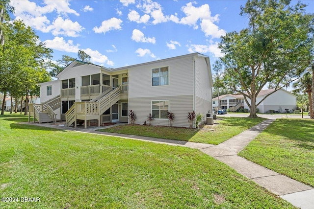 rear view of property with a lawn and cooling unit