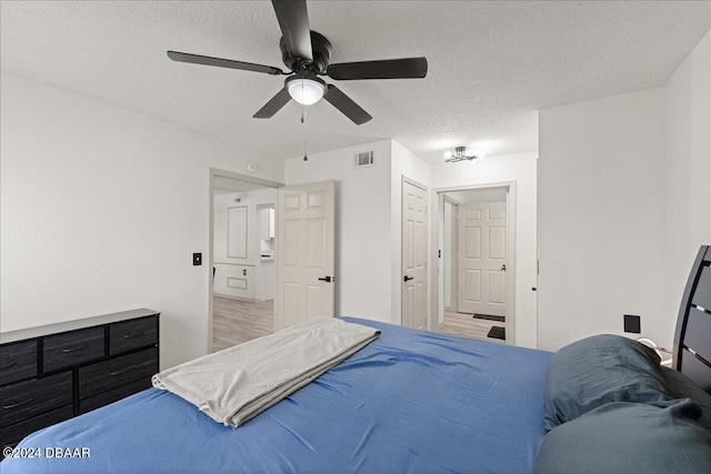 bedroom with a textured ceiling, wood-type flooring, ceiling fan, and a closet