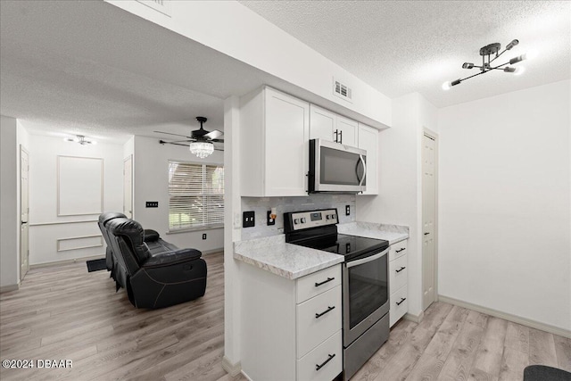 kitchen featuring ceiling fan with notable chandelier, stainless steel appliances, white cabinets, a textured ceiling, and light hardwood / wood-style flooring