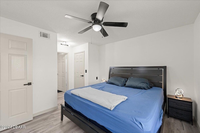 bedroom featuring wood-type flooring, ceiling fan, and a textured ceiling