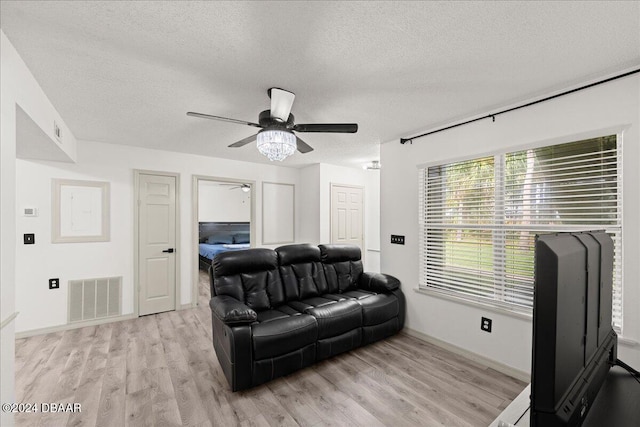 living room featuring ceiling fan, a textured ceiling, and light hardwood / wood-style flooring