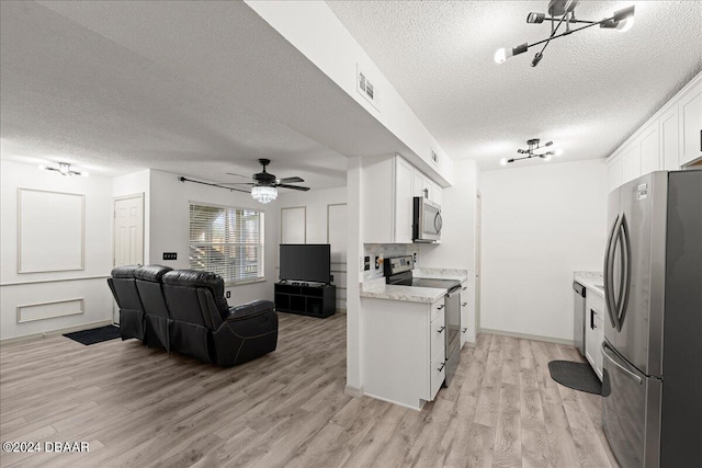 kitchen with white cabinetry, appliances with stainless steel finishes, a textured ceiling, and light wood-type flooring