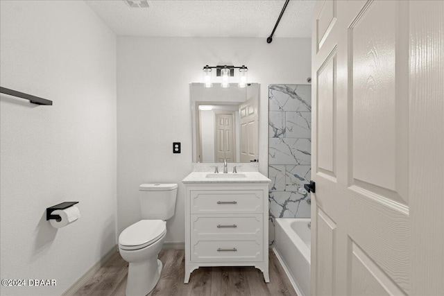 full bathroom with wood-type flooring, toilet, tiled shower / bath combo, a textured ceiling, and vanity