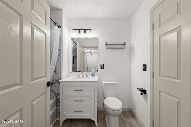 full bathroom with wood-type flooring, a textured ceiling, toilet, and vanity