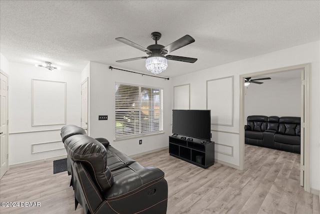 living room featuring light hardwood / wood-style floors, ceiling fan, and a textured ceiling