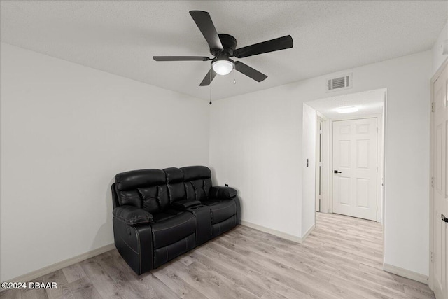 living area with ceiling fan, a textured ceiling, and light hardwood / wood-style floors