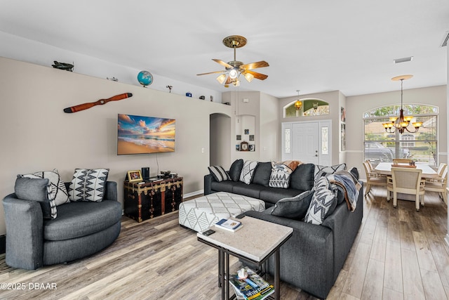 living room with ceiling fan with notable chandelier and wood-type flooring