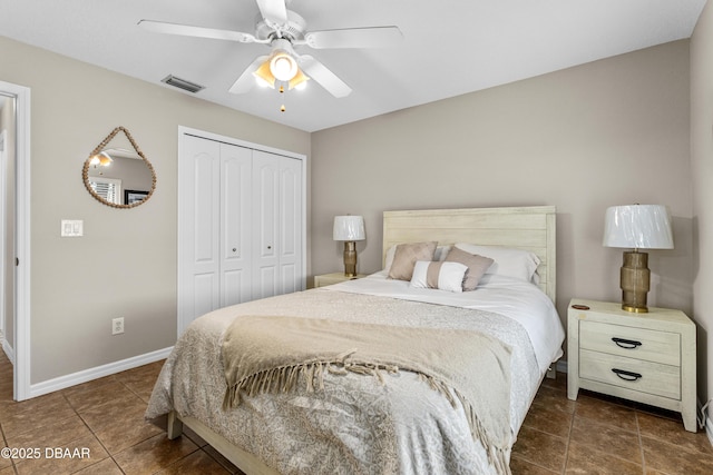 bedroom featuring baseboards, visible vents, dark tile patterned flooring, ceiling fan, and a closet