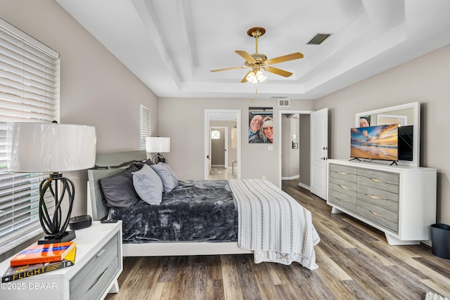 bedroom featuring a raised ceiling, wood-type flooring, and ceiling fan