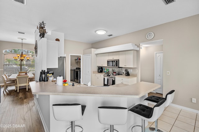 kitchen featuring stainless steel appliances, light countertops, white cabinets, and a peninsula