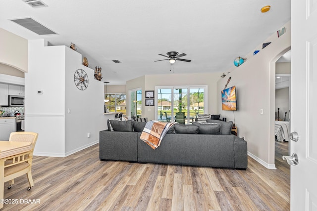 living room featuring light wood-style floors, arched walkways, and visible vents