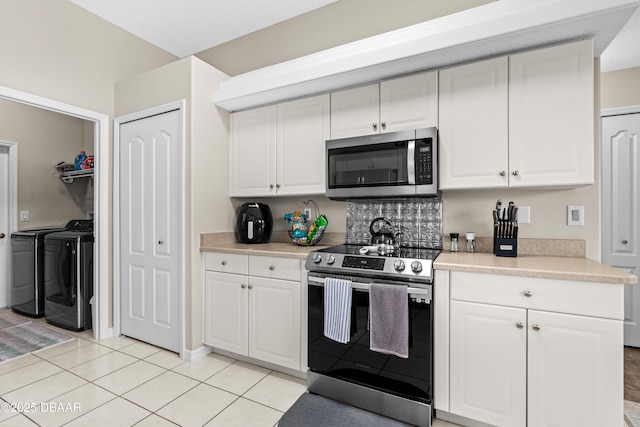 kitchen with stainless steel appliances, white cabinetry, and separate washer and dryer