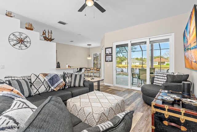 living area featuring ceiling fan, wood finished floors, visible vents, and baseboards