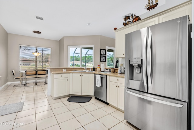 kitchen featuring light tile patterned floors, visible vents, decorative light fixtures, stainless steel appliances, and light countertops